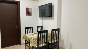 uma mesa com quatro cadeiras e uma televisão na parede em Anna´s apartament em Lushnjë