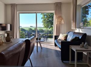 uma sala de estar com um sofá e uma grande janela em Domein Hellebeuk met UITZICHT! Valkenburg/Klimmen em Klimmen