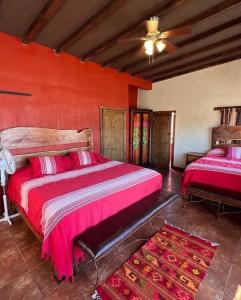 1 dormitorio con 2 camas y pared roja en Casa Concepcion Suites, en Punta Arena