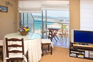 d'un salon avec une table et une télévision ainsi que d'un balcon. dans l'établissement Precioso apartamento en primera línea de playa, à Palamós