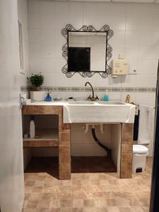 ein Badezimmer mit einem weißen Waschbecken und einem Spiegel in der Unterkunft EL RETIRO in Sanlúcar de Barrameda