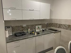 a kitchen with white cabinets and a sink at R&G apartman in Bijeljina