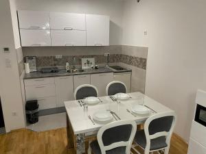 a kitchen with a white table with chairs and a counter at R&G apartman in Bijeljina