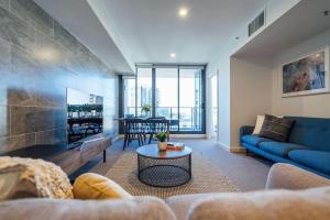 a living room with a blue couch and a table at Sky High on Grote - An Elevated Inner-City Stay in Adelaide
