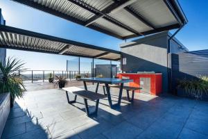 a patio with a picnic table and benches on it at Sky High on Grote - An Elevated Inner-City Stay in Adelaide
