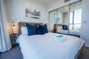 a bedroom with a large white bed with blue pillows at Sky High on Grote - An Elevated Inner-City Stay in Adelaide +37 photos