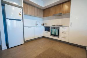 a kitchen with white cabinets and a refrigerator at Sky High on Grote - An Elevated Inner-City Stay in Adelaide