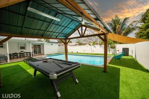 a ping pong table in a backyard with a pool at Calle 8 Marvel - Miami Oasis Retreat L55 in Miami