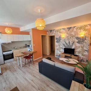 a living room with a blue couch and a kitchen at Chez Raphaël - local à vélos au centre historique in Tonnerre