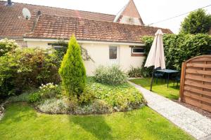 un pequeño jardín con una sombrilla y una casa en Domaine Demoiselles - Cottage de Jeanne, en Hauteville