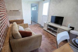 a living room with a couch and a flat screen tv at Domaine Demoiselles Maisonnette in Hauteville