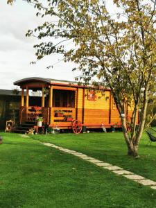 a wooden trailer in a yard with a tree at Roulotte la passe pierre in Pendé