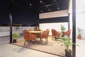a group of chairs and tables in a room with plants at Super Townhouse 1185 Rcc Pride in Hyderabad