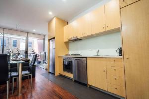 uma cozinha com armários de madeira, uma mesa e uma sala de jantar em Tropicana on Bent Adelaide em Adelaide