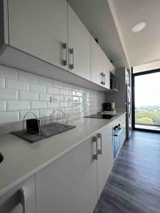 a kitchen with white cabinets and a large window at Panoramic view apt with A/C near SJO Airport & Stadium, Cosmopolitan Tower in San José
