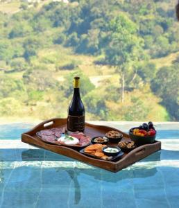 a tray with a bottle of wine and some food at Serrano Exclusive in Tiradentes