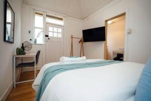 um quarto com uma grande cama branca e uma secretária em Little Chapel on Durham em Glenelg