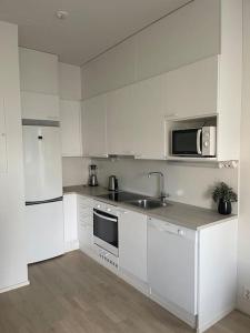 a white kitchen with a sink and a microwave at Location courte durée, jolie appartement lumineux in Vantaa