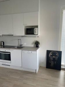 a white kitchen with a sink and a microwave at Location courte durée, jolie appartement lumineux in Vantaa