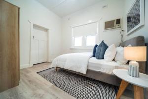 a white bedroom with a bed and a table at Seas The Day on Durham in Glenelg