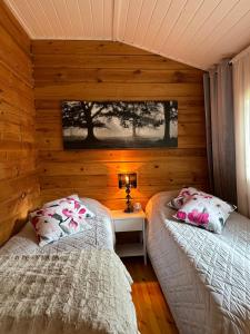 two beds in a room with wooden walls at Cityvilla on the shore of Lake Haapajärvi in Joensuu