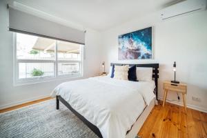 a white bedroom with a large bed and a window at Urban Beach Shack Grange in Grange