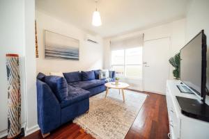 a living room with a blue couch and a tv at Urban Beach Shack - Steps to Grange Beach & Café in Grange