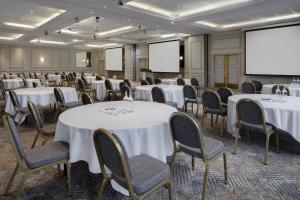 Delta Hotels by Marriott Swansea في سوانسي: قاعة اجتماعات مع طاولات وكراسي وشاشة عرض