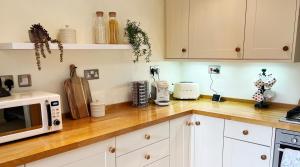 een keuken met witte kasten en een houten aanrecht bij Traditional 2 bedroom Cottage in Stratford-upon-Avon