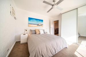 a white bedroom with a bed and a ceiling fan at Serenity by the Sea Grange in Grange