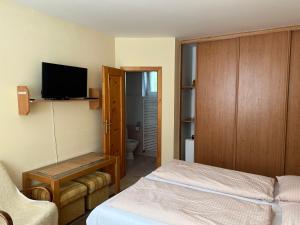 Un pequeño dormitorio con una cama y un televisor. en Privát Pekný dvor, en Rajecké Teplice