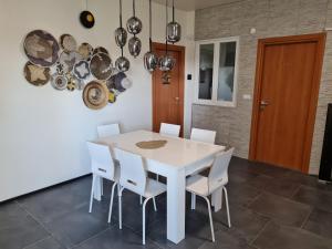 a white dining room with a white table and white chairs at Appartamento del Li-Lioni di Teranga 2 in Platamona