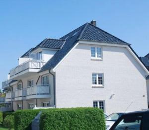 uma grande casa branca com um telhado preto em Kleines Glück Grömitz (ehemals Deichperle) em Grömitz