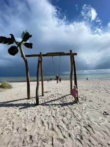 a person sitting on a beach with a swing at Kleines Glück Grömitz in Grömitz