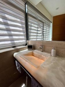 uma casa de banho com um lavatório e uma janela em PENTHOUSE de lujo en las animas! A 5 minutos de plaza Angelópolis em El Gallinero