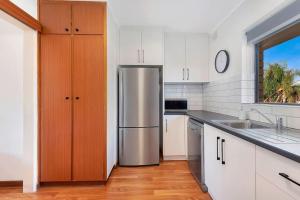 a kitchen with a stainless steel refrigerator and white cabinets at Moments on Moseley Glenelg in Glenelg