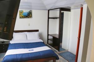 Dormitorio pequeño con cama y espejo en Hospedaje Costa Azul, en Aquitania