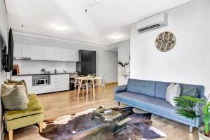 sala de estar con sofá azul y cocina en Recharge on Rundle Adelaide, en Adelaida