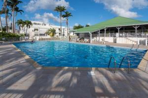een zwembad in een resort met palmbomen bij Superbe studio avec Piscine, au coeur de la Marina! Village Soleil ! in Le Gosier