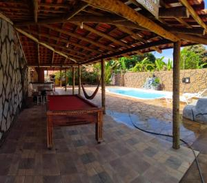 einen Billardtisch unter einer Pergola neben einem Pool in der Unterkunft Rancho Andrade in Três Marias