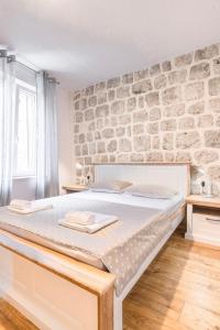 - un grand lit dans une chambre dotée d'un mur en pierre dans l'établissement Apartments Florian, à Lopud