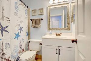 a bathroom with a toilet and a sink and a mirror at Oceanview Resort*Hot tub*North Topsail Beach in North Topsail Beach +30 photos