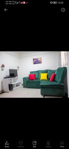 uma sala de estar com um sofá verde com almofadas coloridas em Tranquil 2 homes em Nanyuki