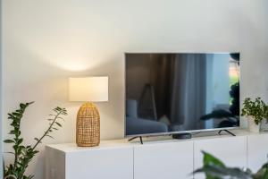 a television on a white cabinet with a lamp on it at Ficcus Home in Caniço