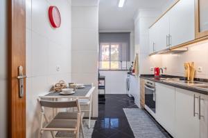- une cuisine avec des placards blancs, une table et des chaises dans l'établissement Ficcus Home, à Caniço