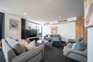 uma sala de estar com sofás e uma televisão de ecrã plano em Onyx on North Tce CBD Penthouse Pool Parking em Adelaide