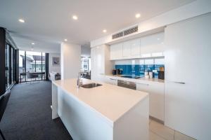 uma cozinha com armários brancos e uma grande ilha em Onyx on North Tce CBD Penthouse Pool Parking em Adelaide