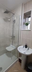 a white bathroom with a shower and a sink at Lister Park Bradford Stylish 1bed Coach House - Quiet & Tranquil Cottage & Parking in Shipley