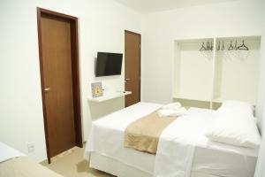 a white bedroom with two beds and a television at Casa a 560 metros da Praia de Ponta Negra in Natal +24 photos