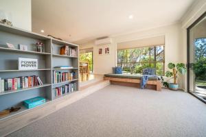 Adelaide Hills Retreat - Surrounded by Nature في Ironbank: غرفة معيشة مع مقعد ورفوف كتب